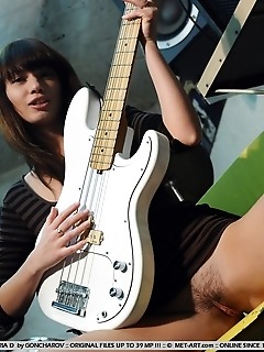 Ultra seductive brunette baring her large breasts and untrimmed bush with an electric guitar.